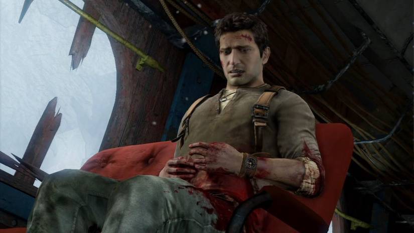 Nathan Drake sitting while injured with snow blowing past him