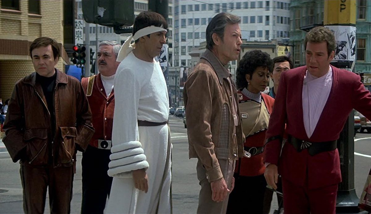 Kirk, Sulu and Uhura stand on a street in Japan with people in Star Trek IV The Voyage Home